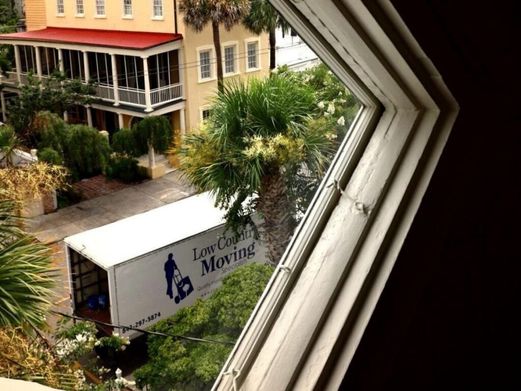 Low Country Moving Specialists truck parked with its rear doors open, seen through an upstairs window above the street